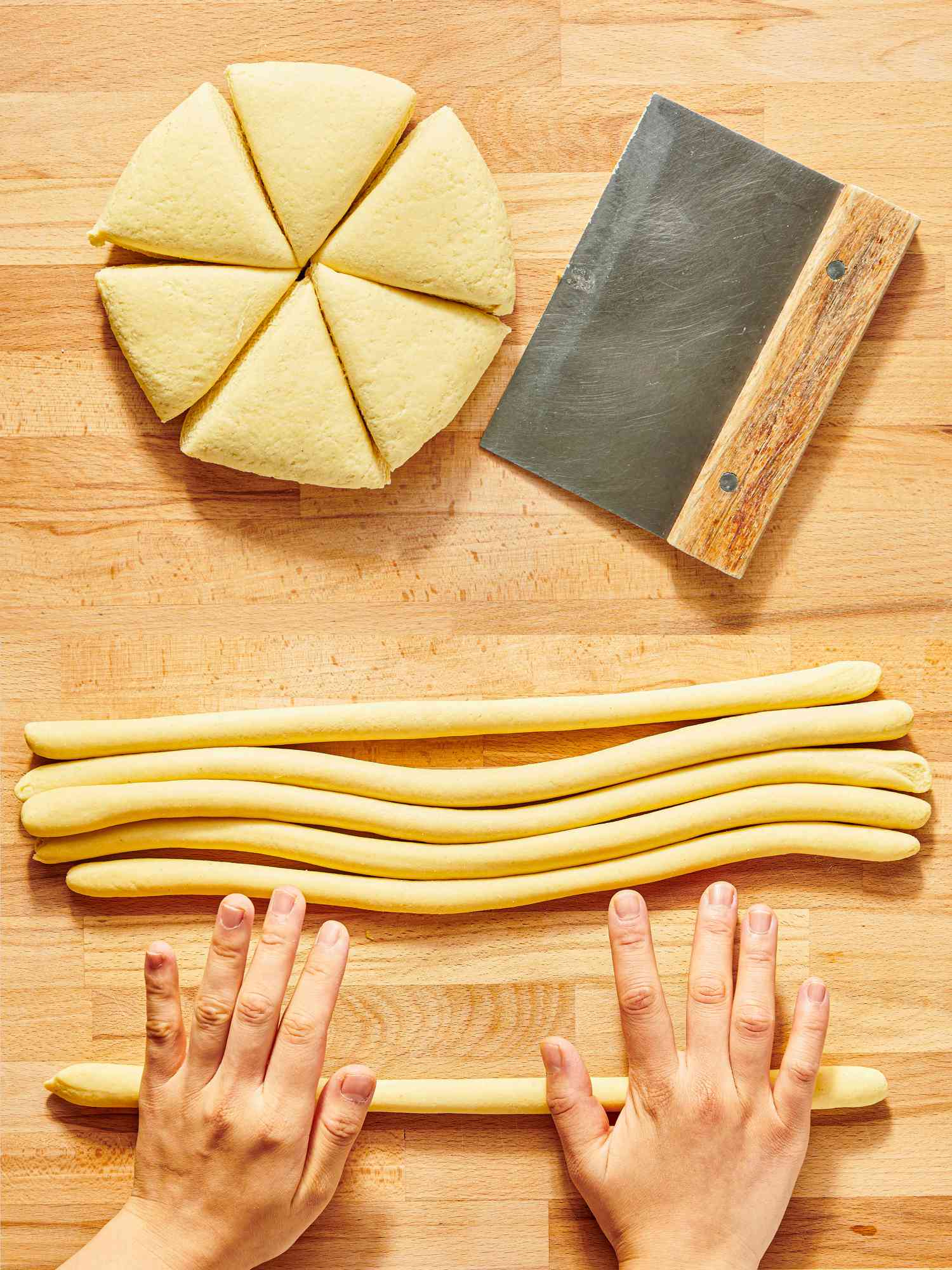 2 image collage. Top: Dough cut into 6 equal pieces with a bench scraper on a wooden surface. Bottom: dough rolled out into even sized ropes on wooden surface 