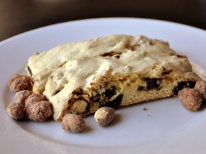 Closeup of Candied Almond Chocolate Chip Biscotti, served on a plate with cinnamon coated almonds scattered around.