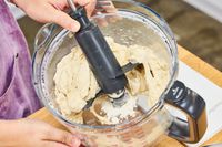 A person removes the blade from the Breville 16-Cup Sous Chef Peel & Dice Food Processor