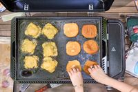 Hamburgers are made on the Weber Slate 22 inch Rust-Resistant Tabletop Griddle