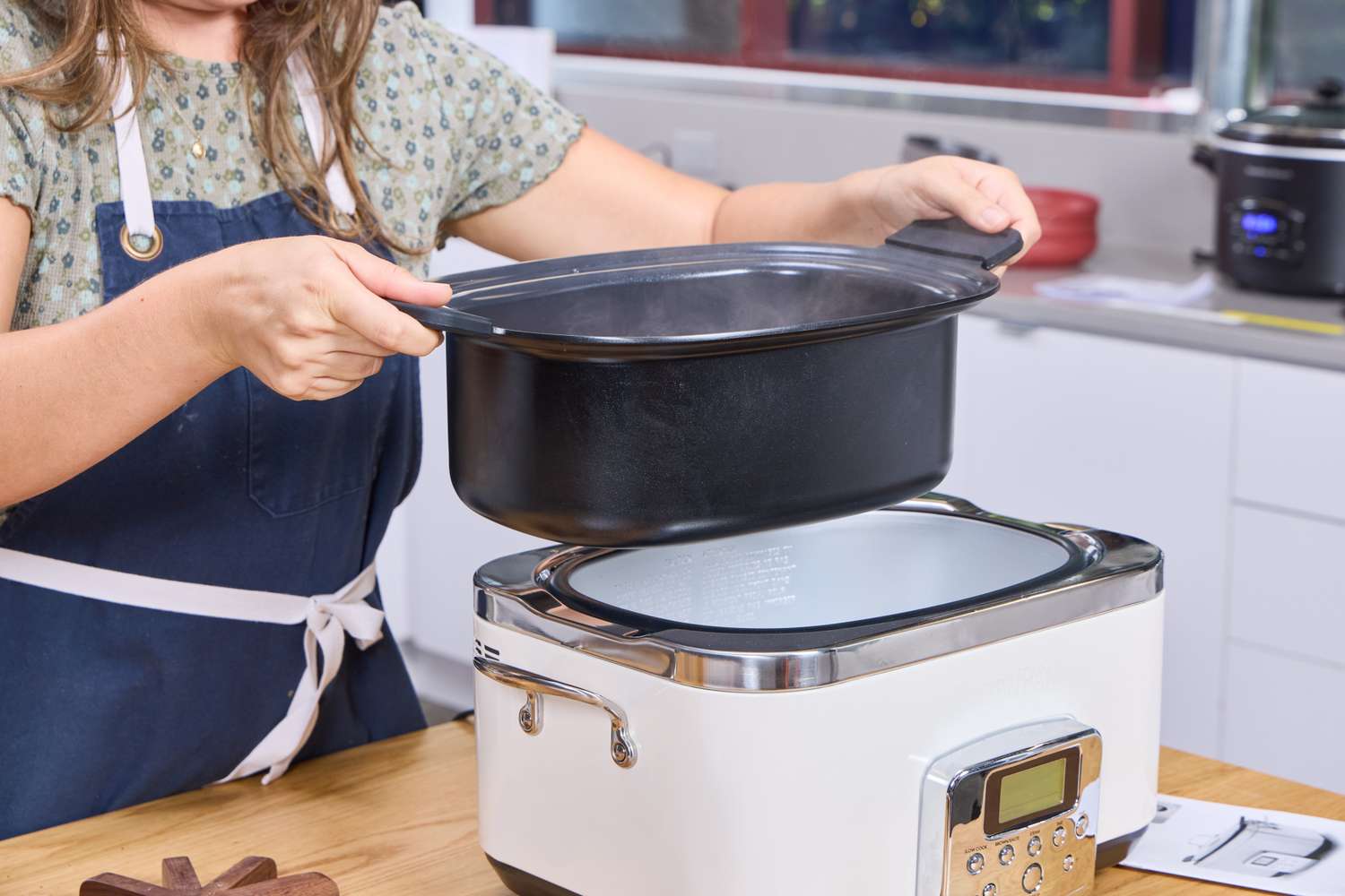 A person lifts the interior pan from the GreenPan Elite 6-Quart Slow Cooker