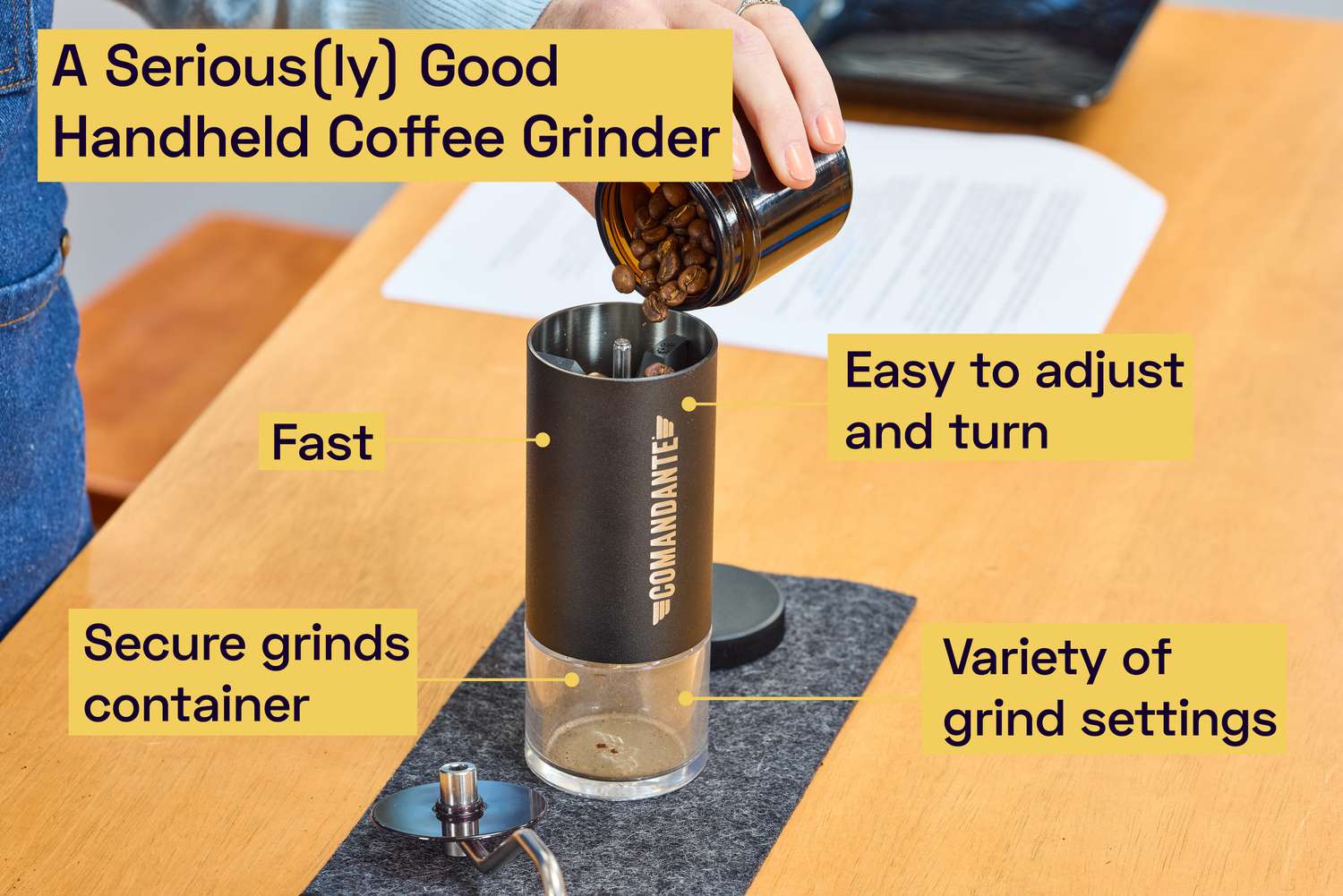 A person pouring coffee beans into a handheld coffee grinder.