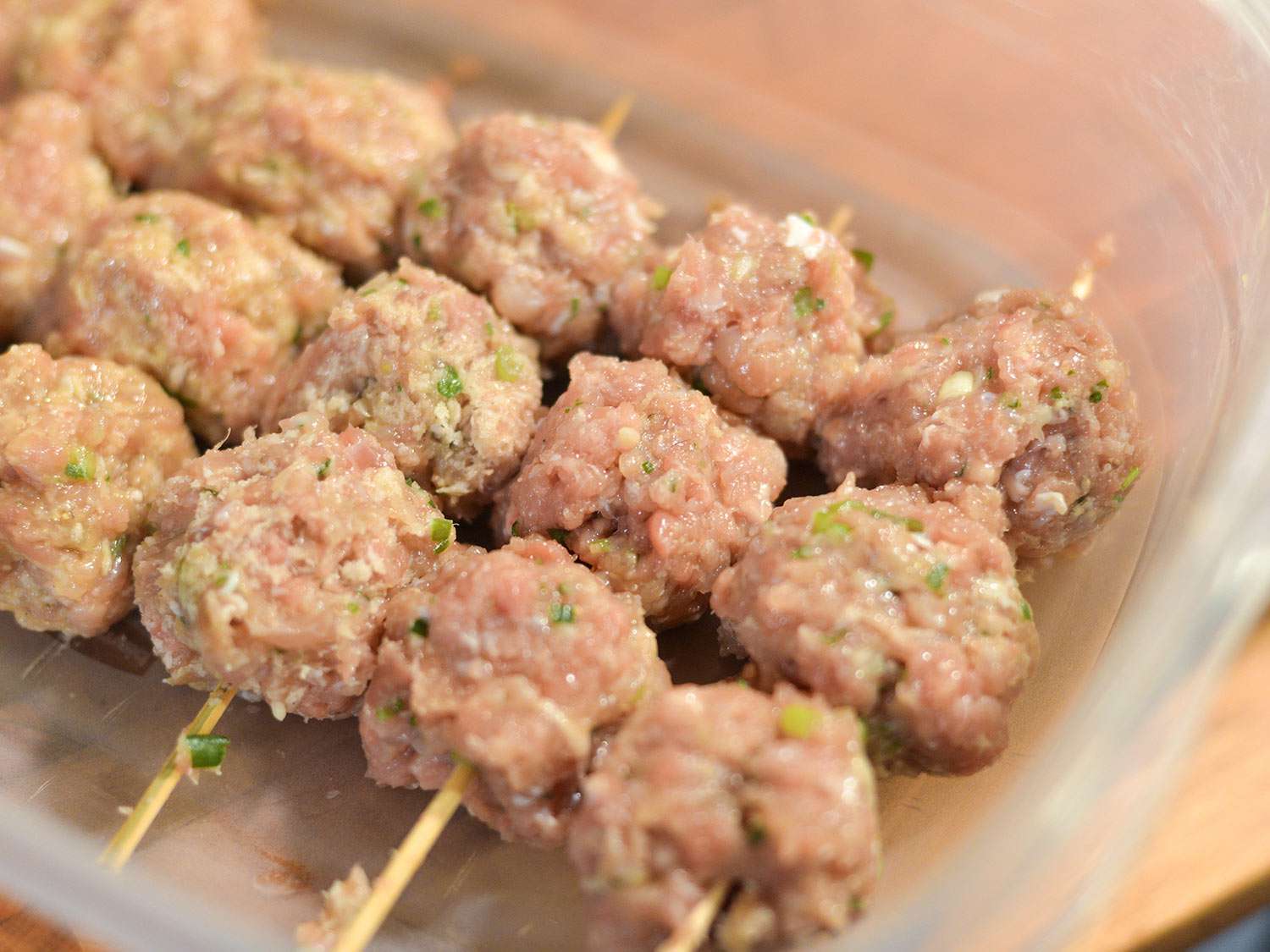 Skewers of tsukune meatballs arranged in a baking dish.