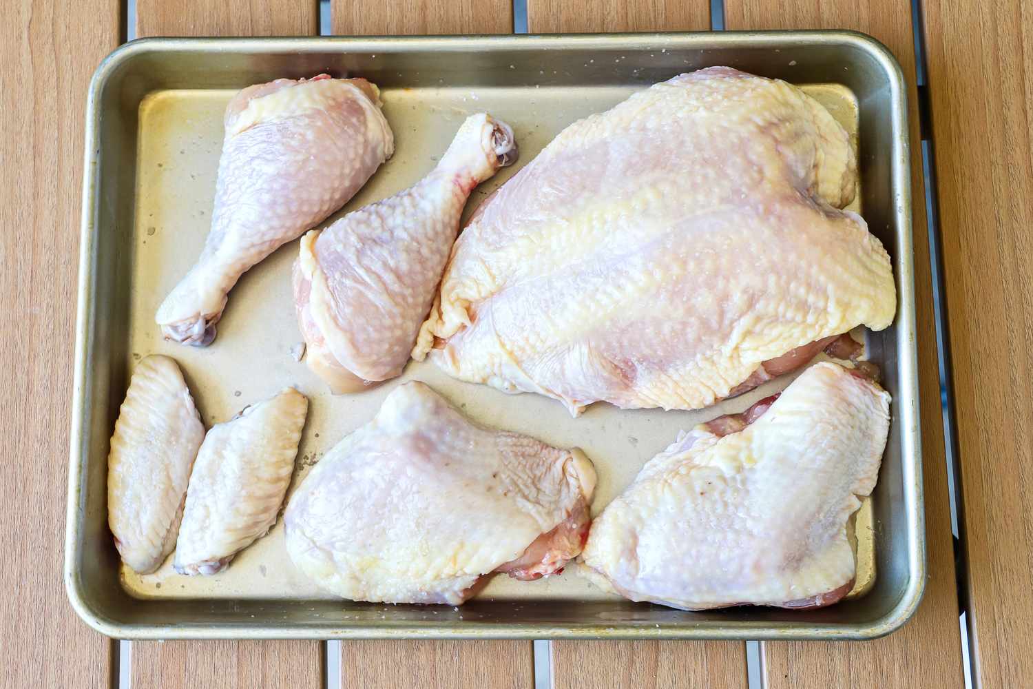 Various raw Butcherbox chicken cuts placed on a rectangular baking tray