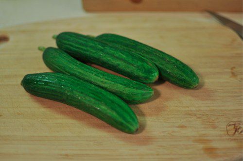Four cucumbers on a cutting board.