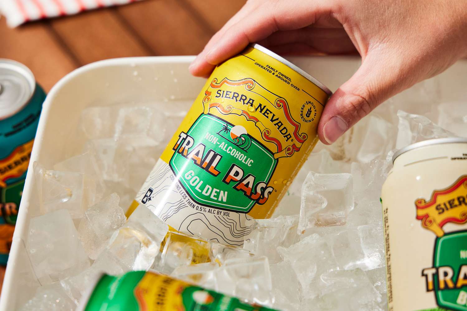 a hand pulling out a can of Sierra Nevada trail pass golden out of a bucket of ice
