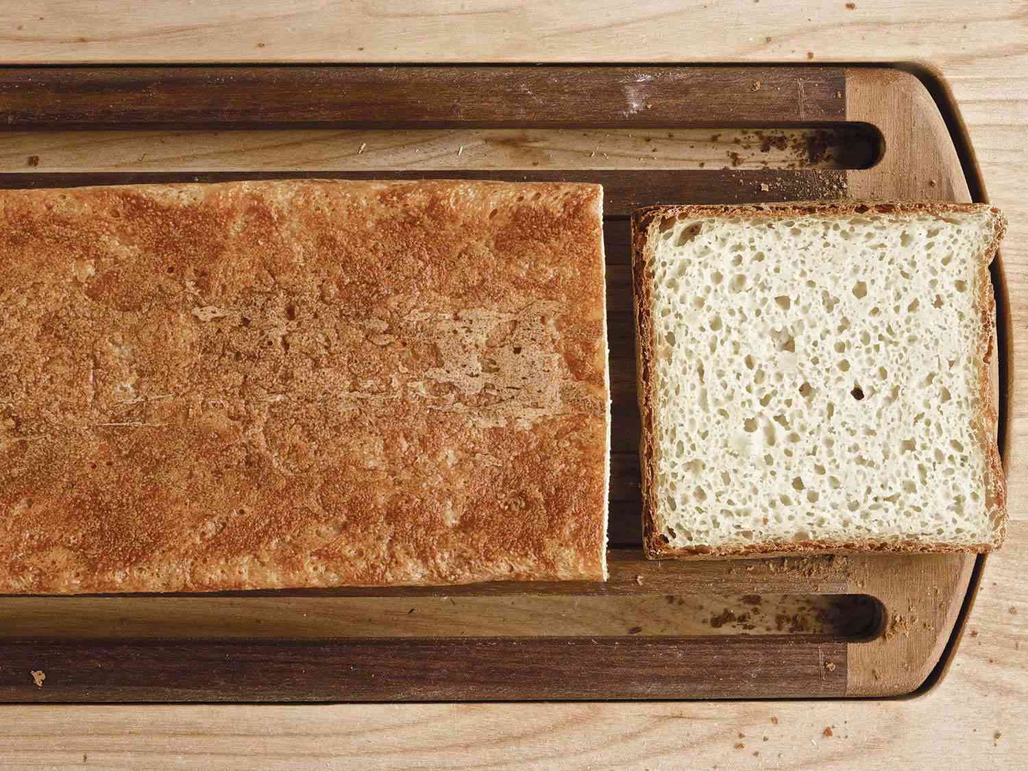 Overhead shot of a loaf of gluten-free potato bread on a wooden board, with a slice cut from the end