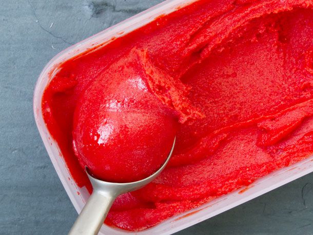 A tub of strawberry sorbet with an ice cream scoop.
