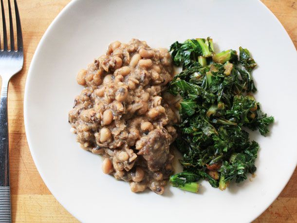 Overhead view of black-eyed peas with ham hock, served with a side of braised greens.