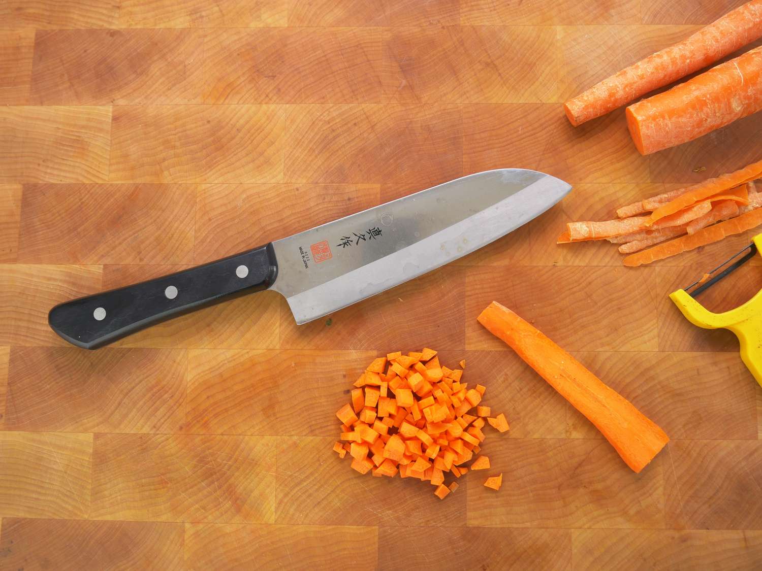 Mac superior santoku on a wooden cutting board with chopped carrot