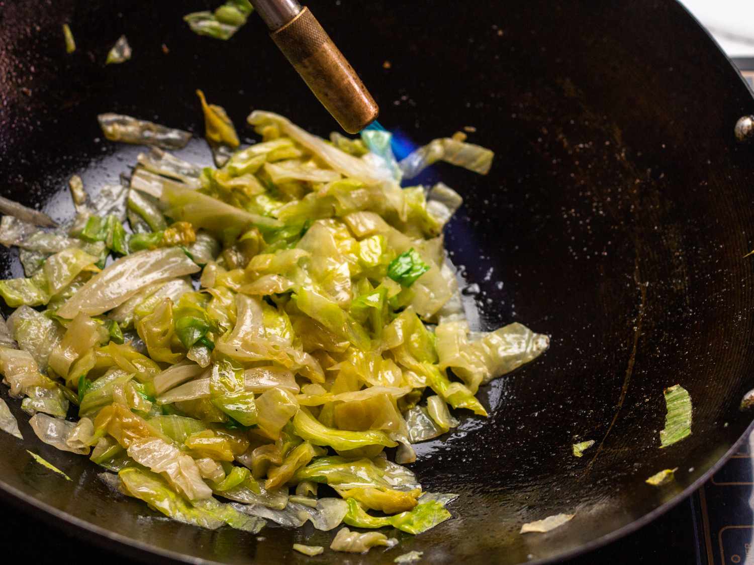 a torch hitting the oils to infuse dish with wok-hei