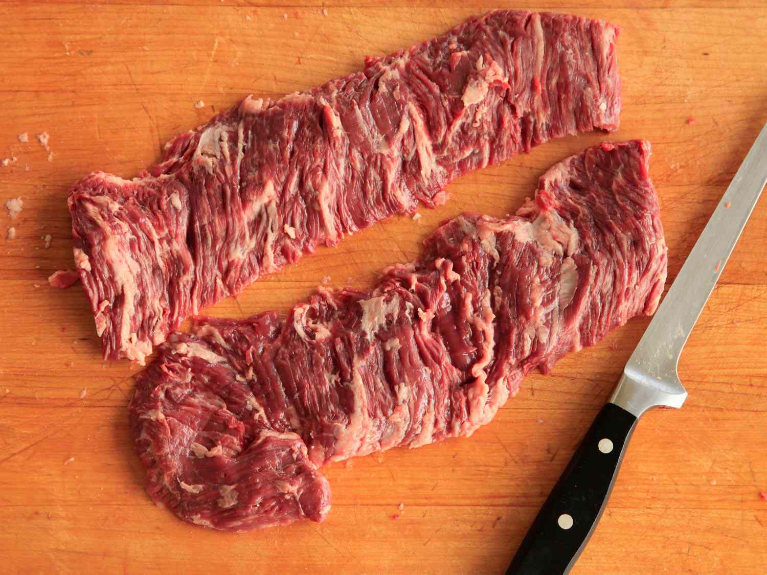 Two pieces raw skirt steak on a wooden surface