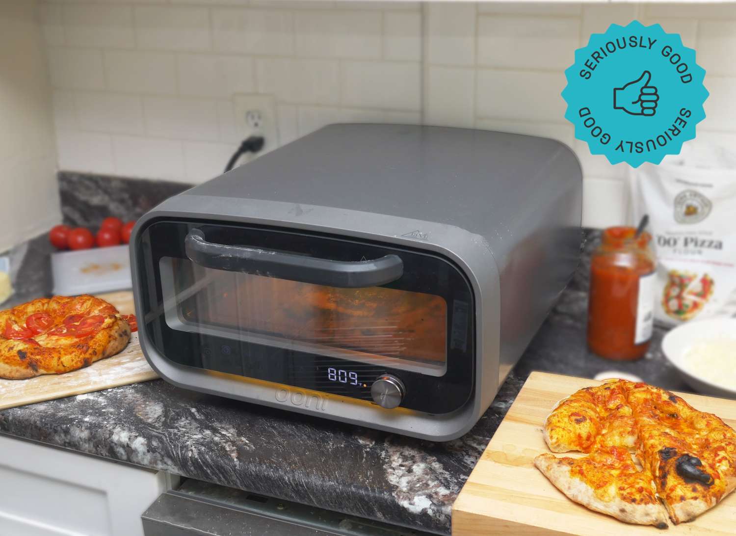 Compact pizza oven on a kitchen counter with freshly baked pizzas nearby