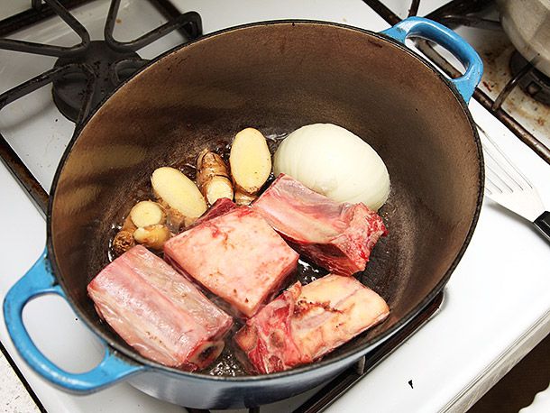 English-cut short ribs, thick slices of ginger, and half an onion browning in a Dutch oven.