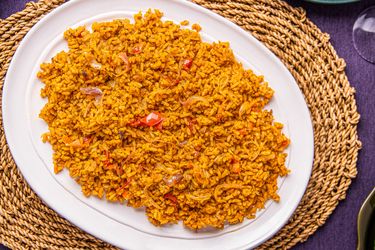 A plate of Nigerian Jollof rice served on a woven mat