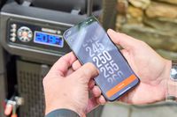 A person controls the Masterbuilt Gravity Series 1150 Digital Charcoal Grill and Smoker with an app