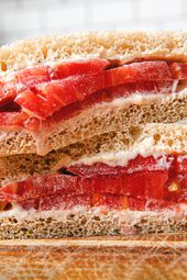Classic tomato sandwich on a cutting board, cut diagonally and stacked