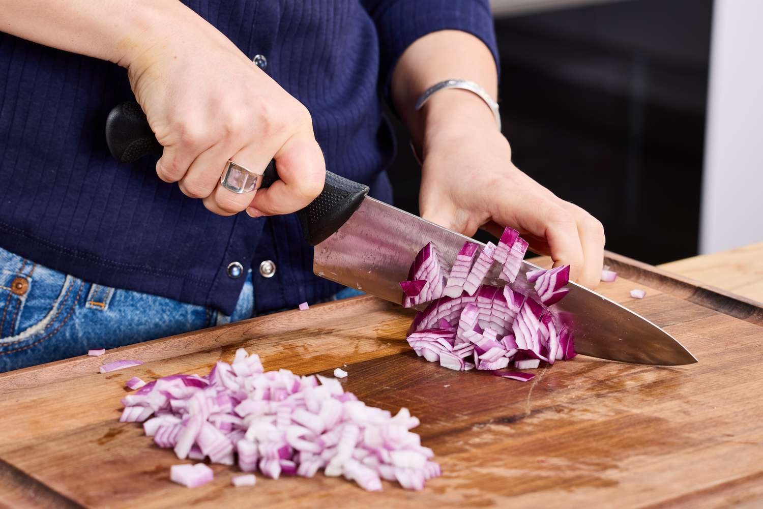 A person dices red onion with the Mercer Culinary 8-Inch Millennia Chef's Knife