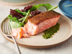 Crispy pan-seared salmon fillet served on a plate with greens