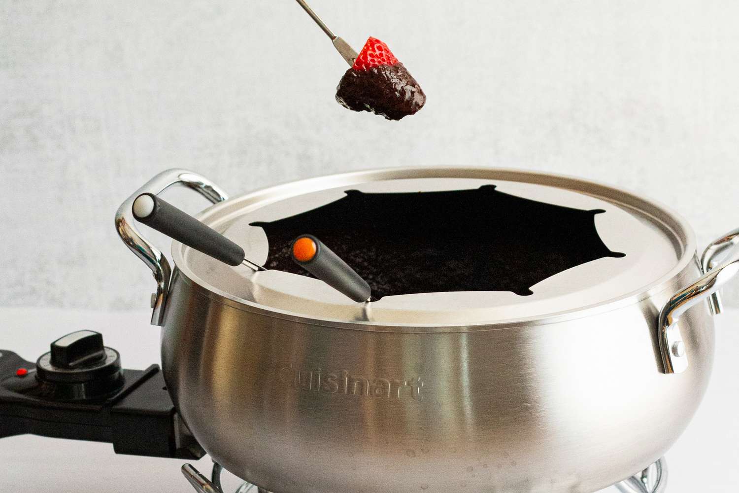 a person removing a strawberry dipped in chocolate