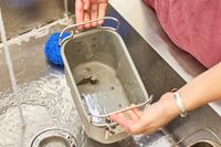 A person washing the Zojirushi Home Bakery Virtuoso Plus Bread Maker basket