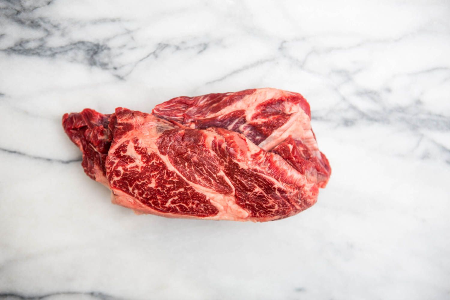 A marbled piece of chick steak on a stone counter.