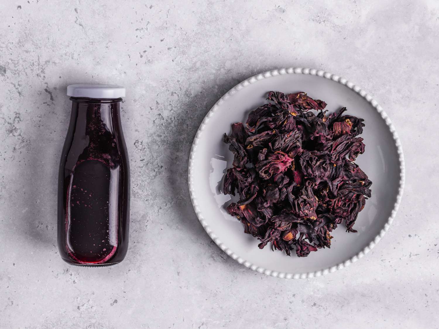 Zobo and hibiscus sabdariffa next to each other on a grey marbled surface