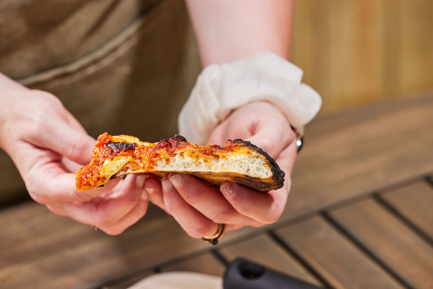 Two hands showing the side of a slice of pizza made in the Gozney Roccbox Pizza Oven