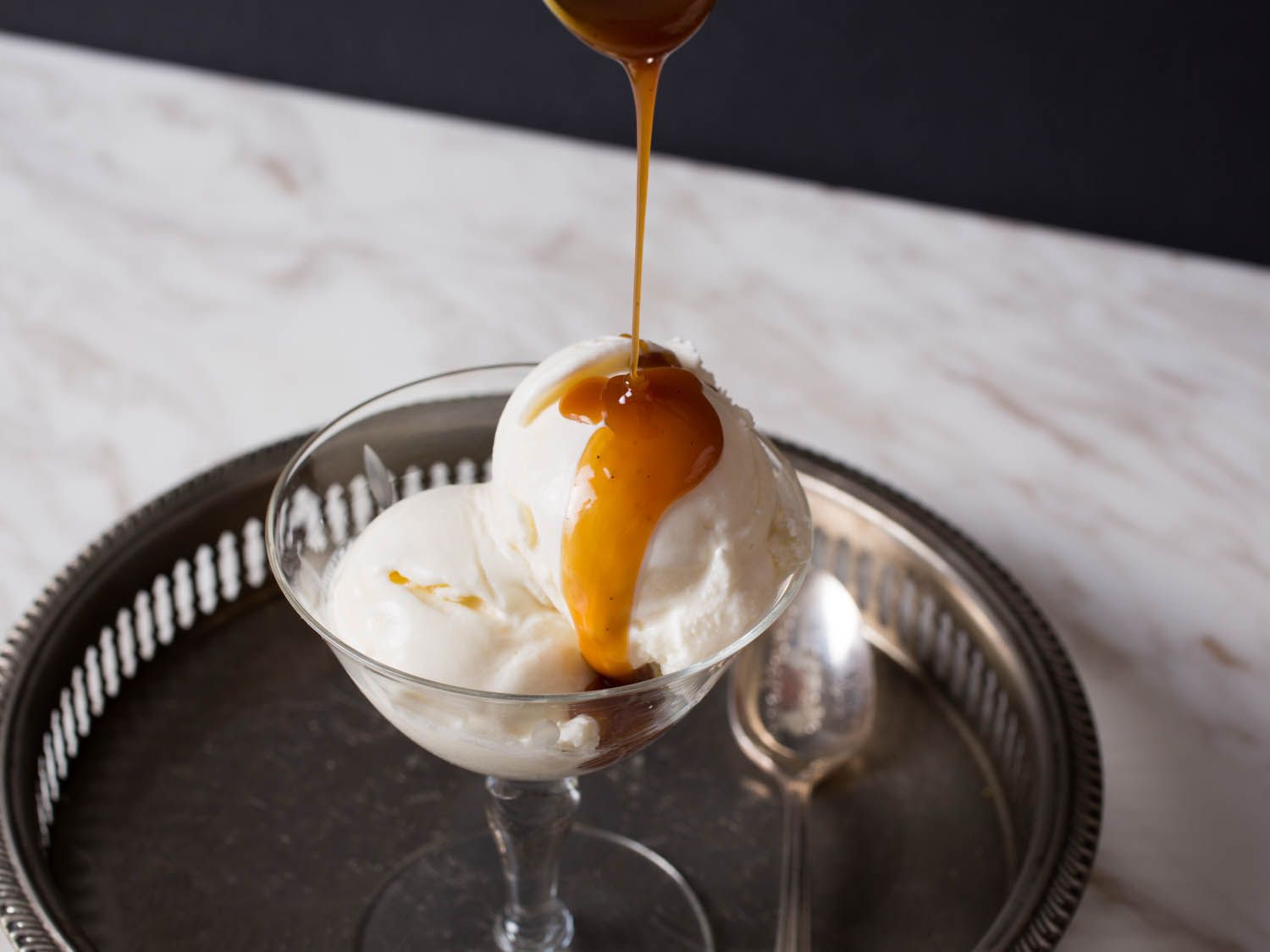 The serving bowl of ice cream is drizzled with caramel sauce.