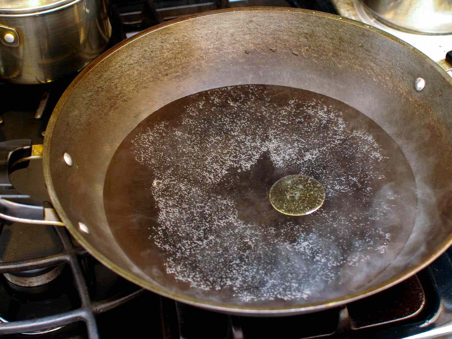 Water and a small amount of oil is brought to a boil in a wok.