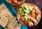 Overhead shot of poached shrimp in tomato-based sauce and diced avocado served in cocktail glass