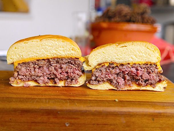 Grilled hamburgers, sandwiched in buns and cut in half to reveal the interior of the patties.