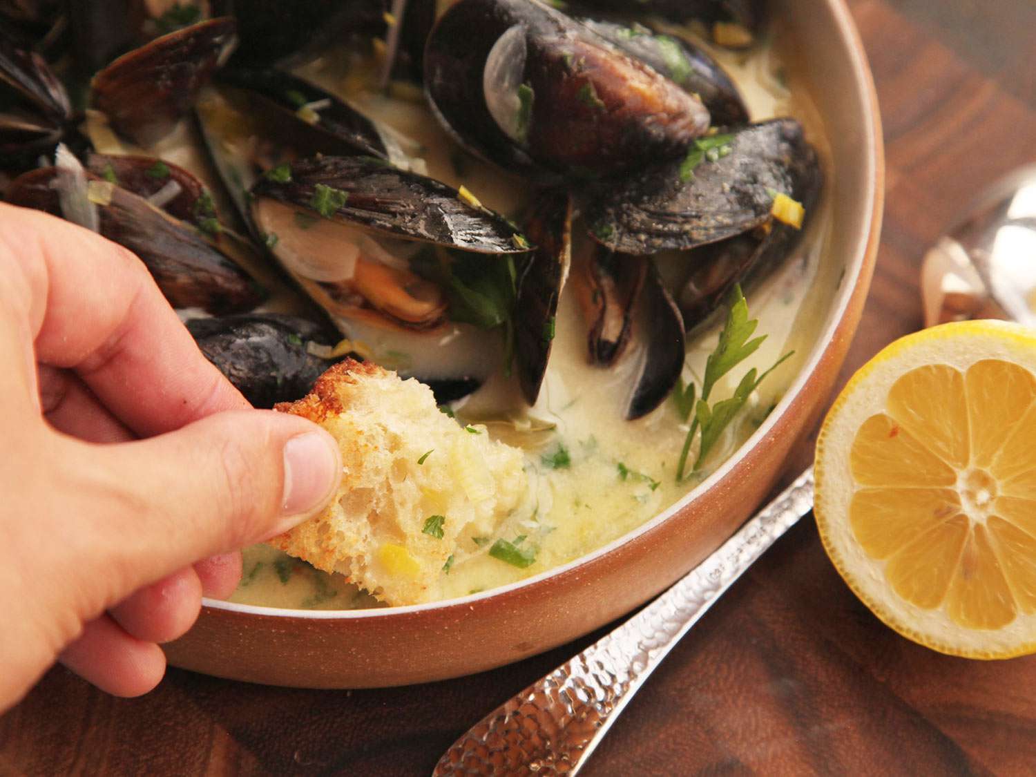 Author dipping a portion of toasted bread into the enriched mussel broth.