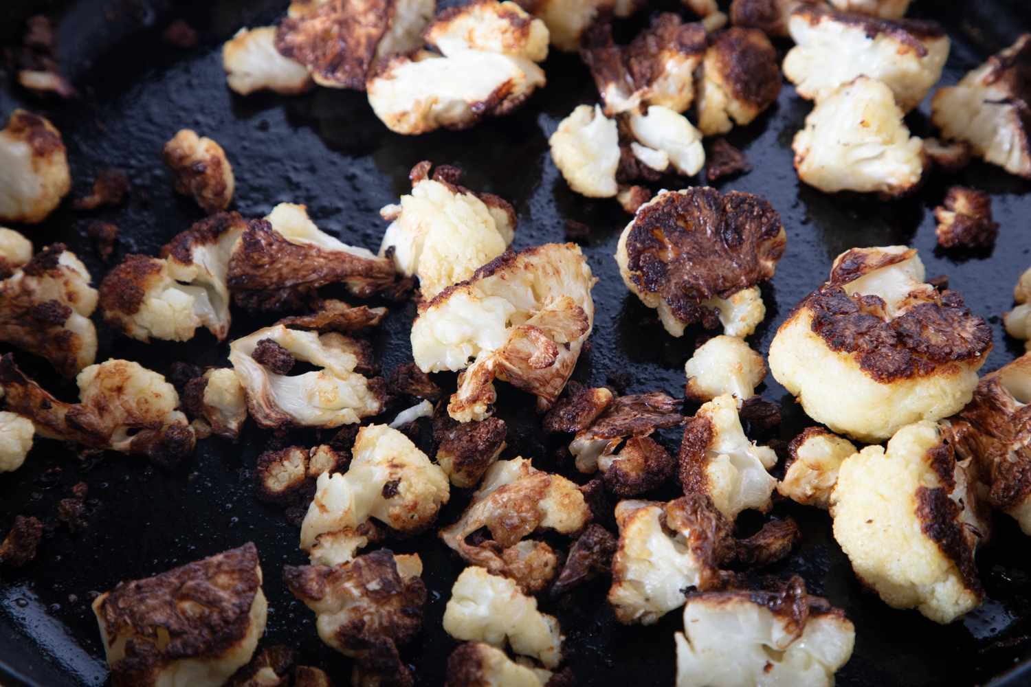 Chopped and roasted cauliflower pieces on a skillet