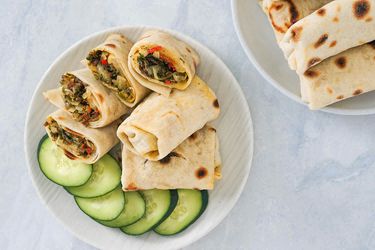 Overhead of a place of halved machaca guisada beef burritos with slices of cucumber.