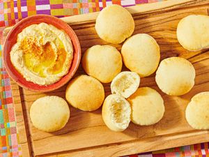 A wooden board with pita bread and a bowl of hummus