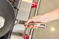 A person holds the handle of the Misen 12 Inch Carbon Steel Wok