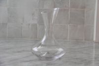 A closeup of the empty Godinger glass wine decanter on a marble surface