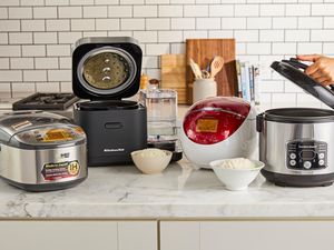 Four rice cookers on a kitchen countertop.