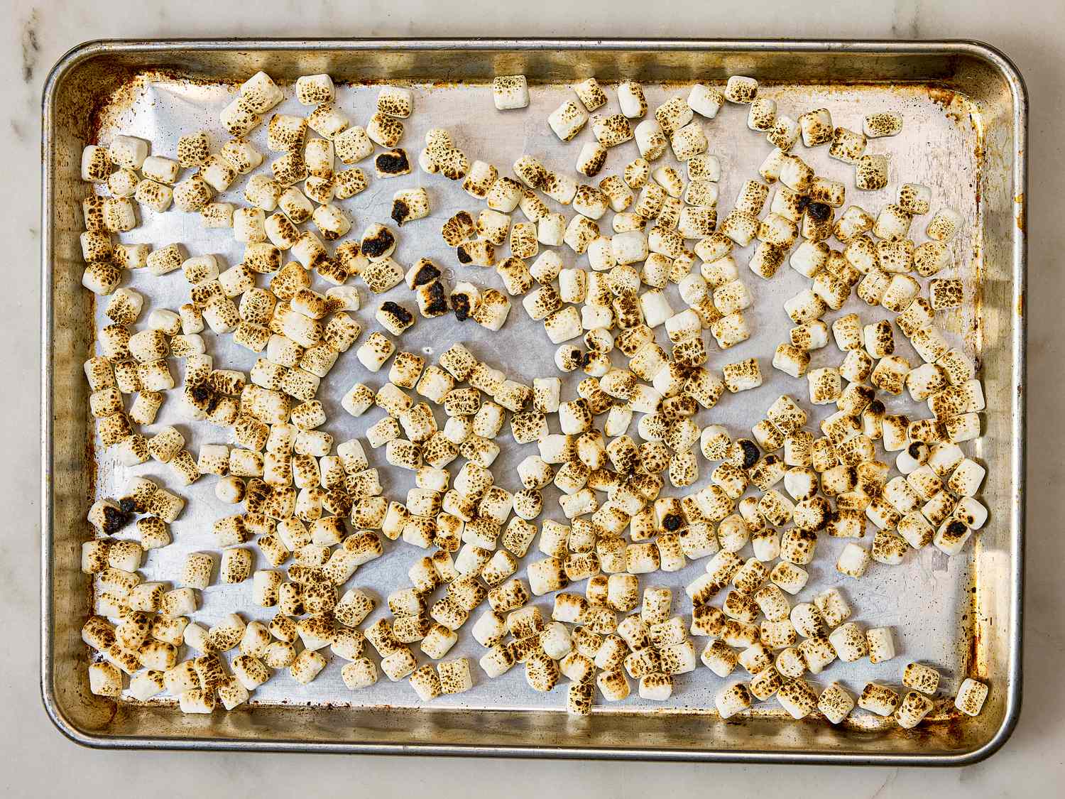 Toasted marshmallows spread on a baking sheet lined with parchment paper
