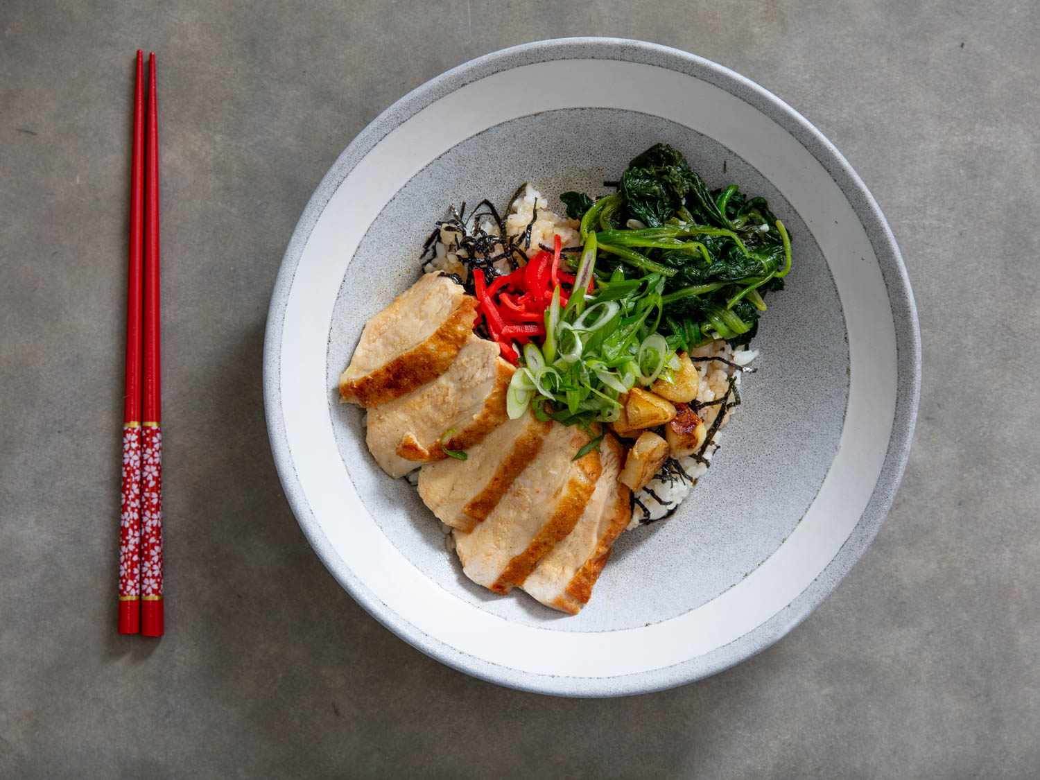 Overhead view of chicken donburi with spinach, served in a ceramic bowl.