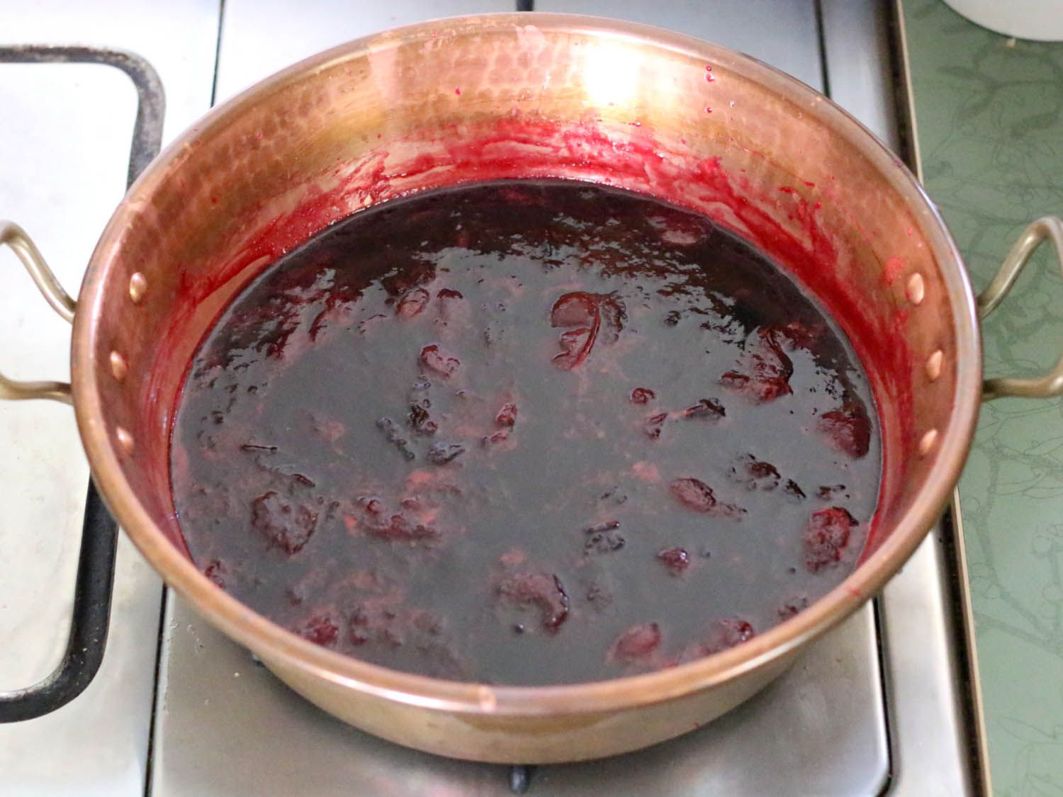 Plums being cooked into jam in a copper jamming pot.