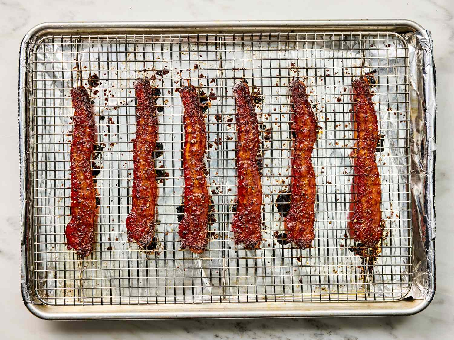 Crispy food item strips arranged on a wire rack over a foillined baking sheet