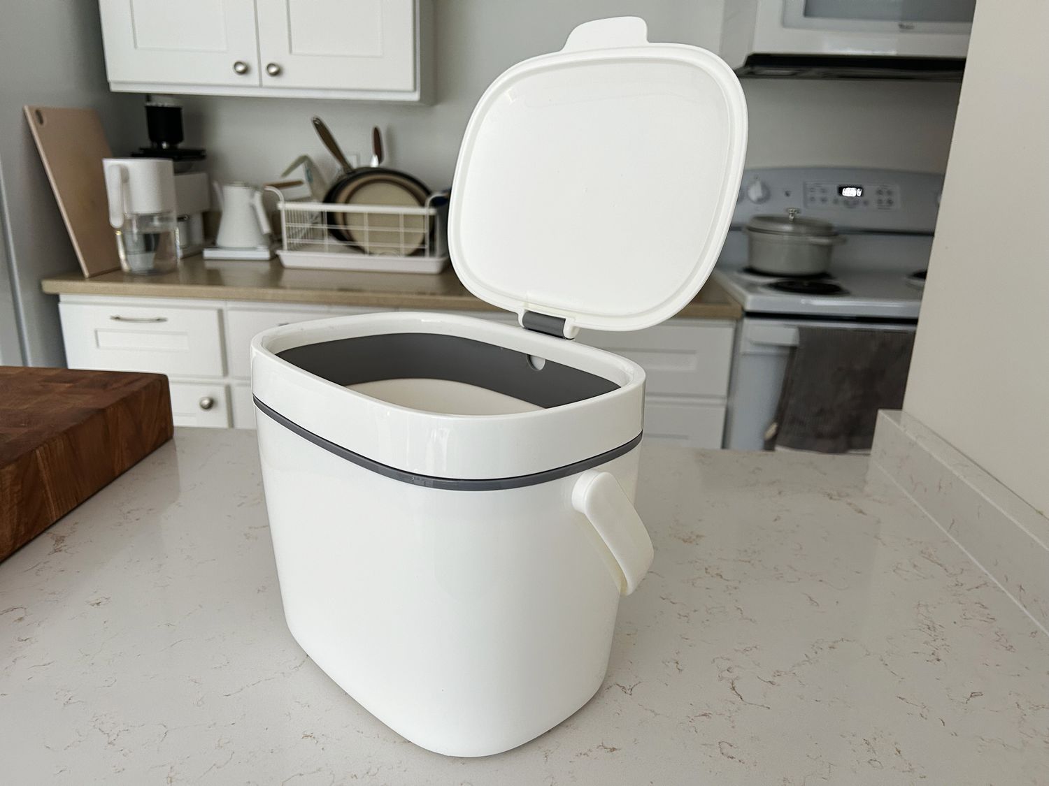 A white plastic compost bin on a granite countertop