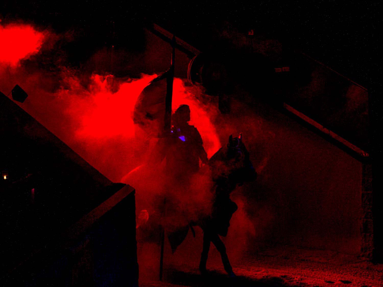 A knight on horseback entering the arena at Medieval Times in a cloud of smoke and red light