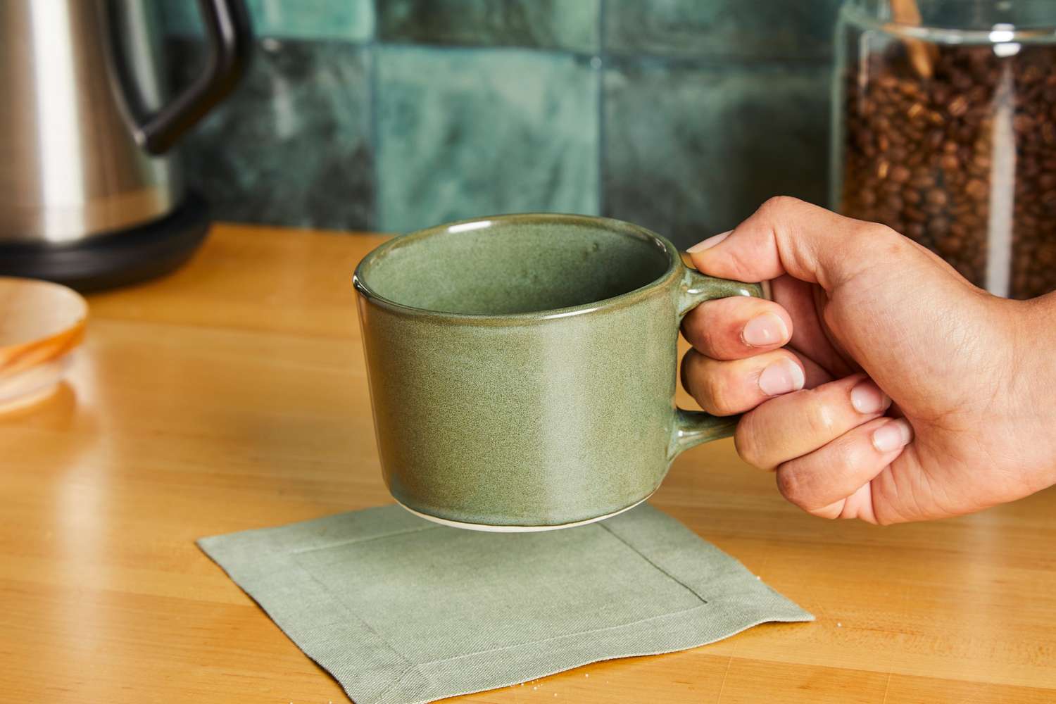 A person holding onto a Haand coffee mug.