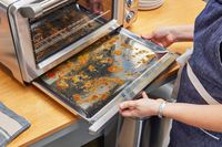 Two hands holding a dirty tray from the Breville the Smart Oven Air Fryer