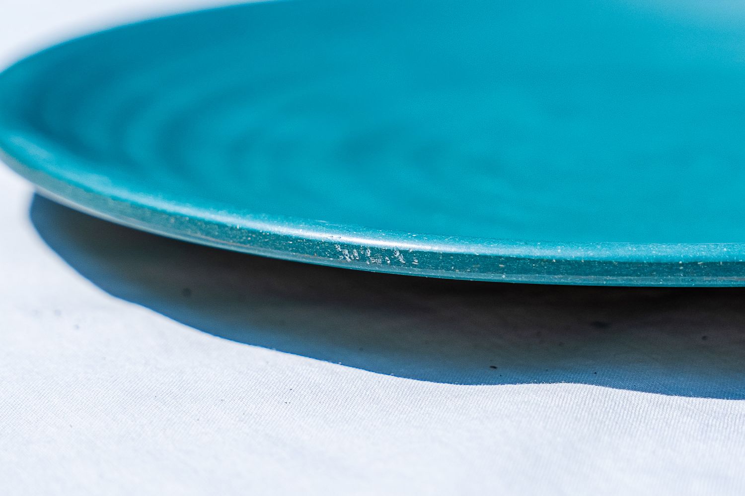 A closeup on a scratch of a blue outdoor dinnerware plate