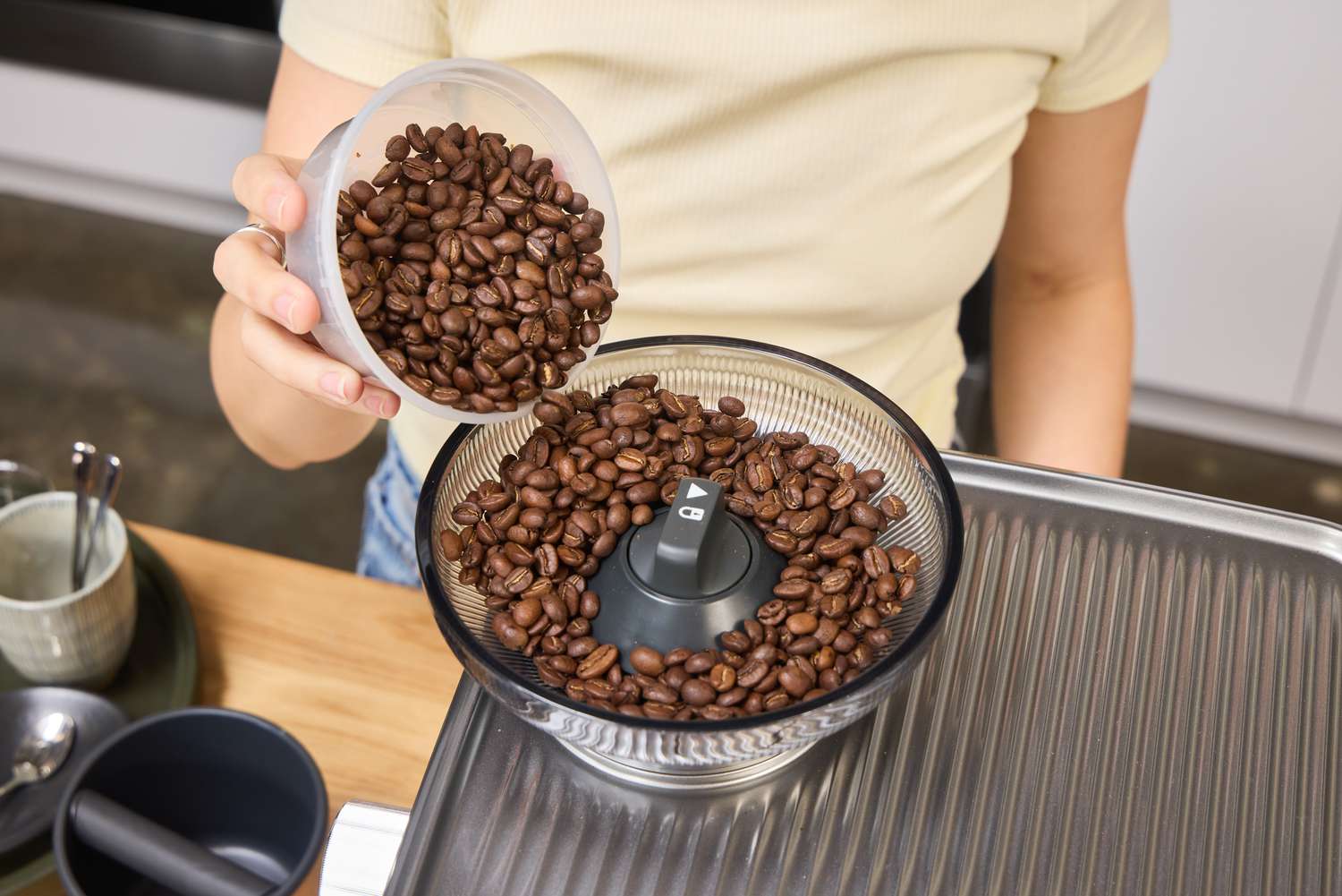 A person pours espresso beans into a grinder on the Breville The Oracle Jet Espresso Machine