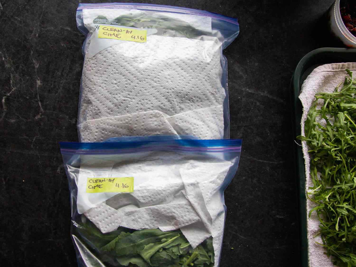 Overhead of two towel-lined zipper lock bags of clean cime di rapa.
